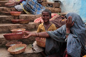 Balaaditya, un bambino "Dalit" (un intoccabile fuori dal complesso e rigido schema delle caste indiane) mi accoglie con questo splendido sorriso mentre la mamma chiede l'elemosina porgendo il canestro di vimini ad un pellegrino di passaggio per raccogliere qualche monetina.  I Dalit, o intoccabili, o Paria, non appartengono a nessuna delle quattro caste ufficiali e vanno evitati, emarginati, non vanno neppure sfiorati perchè considerati impuri, dato che a loro dalla notte dei tempi vengono affidate le attività più umili, degradanti e pericolose (come la conciatura delle pelli, la pulizia delle latrine, la manipolazione dei cadaveri). Secondo un antica leggenda Hindu, il nascere da un padre fuoricasta è motivato dalla credenza che qualche avo sia stato un peccatore, la cui anima pertanto si reincarna nelle generazioni successive con l'intento di purificarsi. Soprattutto nelle zone rurali dell'India, dove l'impronta delle tradizioni è più evidente e, d'altro canto, le angherie messe in campo dalle caste più alte nei loro confronti risultano più pesanti, i Dalit subiscono discriminazioni, vessazioni fisiche e psicologiche di ogni sorta: a loro viene negato l'accesso ai pozzi, alla proprietà terriera, non hanno possibilità di interagire con gli indiani di casta più elevata, pena la giustizia sommaria adottata dal popolo: il linciaggio. Il futuro di questo bimbo non è certamente roseo. Dintorni del Tempio Yallamma Devi, villaggio di Saundatti, regione del Karnataka, India 2015.