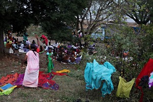 Accanto al fontanile di un pozzo, poco più sotto rispetto all'accampamento occupato dai pellegroini (posto sulla collina Yallammagudda, di fronte al Tempio Yallamma Devi di Saundatti), le donne Hindu si lanciano gli abiti, precedentementi lavati, per stenderli sulle siepi e sui ramoscelli in modo che si asciughino al sole ed all'aria. Regione del Karnataka, India 2015.