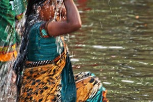 Primo piano del rituale del bagno sacro presso la grande piscina alimentata dal Saundatti Lake: una donna Hindu versa l'acqua sul capo, sui capelli e sul corpo. Successivamente, con molta discrezione, cambierà i vestiti con l'aiuto di altre pellegrine per liberarsi dal vecchio ed accettare il nuovo (perfettamente rappresentato dal sorgere delle prima luna nuova dell'anno). Villaggio di Saundatti, regione del Karnataka, India 2015.