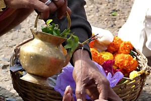 Primo piano di una cerimonia propiziatoria condotta da un santone nei confronti di un fedele hindu: la guida spirituale, recitando dei mantra (preghiere), versa l'acqua benedetta da una piccola anfora (dove sono posti gli incensi e delle erbe considerate magiche) direttamente sulla mano del pellegrino. Spesso queste pratiche spirituali ed esoteriche non risultano legate ad alcun culto religioso particolare: i fedeli si rivolgono alle guide spirituali per trovare sostegno in varie circostanze della loro esistenza (nel caso di una grave malattia, la nascita di un figlio, una promozione nel lavoro o,addirittura, il semplice acquisto di un'autovettura nuova). In India la spiritualità è strettamente associata alla religione hinduista (in particolare) e spesso si identifica con essa, ma molti individui si rivolgono a queste figure per ricercare conforto alle loro paure ed insicurezze, ritenendo di affidarsi in tal modo ad un'entità superiore che possa aiutarli ad ottenere la redenzione o risolvere determinati problemi. Si può ipotizzare che i fedeli giungano a considerare questi santoni come se fossero degli psicoterapeuti. Il pericolo, non sempre così ipotetico, è che questo tipo di relazione e di intimità creata con i devoti possa offrire ad alcuni predicatori (almeno a quelli più scaltri e con meno scrupoli che intravedono grosse opportunità di guadagno) la possibilità di sfruttare a loro favore la vulnerabilità di coloro che si rivolgono con fiducia a questo tipo di pratiche, estendendo la loro influenza oltre i supposti ambiti di competenza spirituale. Dintorni del Tempio dedicato alla Dea Yallamma, villaggio di Saundatti, Regione del Karnataka, India 2015.