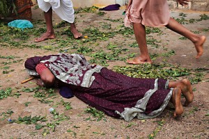 Una donna Hindu si prosta sdraiandosi a terra e pregando in segno di devozione e reverenza nei confronti della Dea Yallamma: sul terreno i rametti e le foglie della pianta di Neem (pianta considerata sacra) abbandonati dagli altri pellegrini. Dintorni del Tempio dedicato alla Dea Yallamma, villaggio di Saundatti, Regione del Karnataka, India 2015.