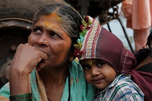 Chaitaly, una bambina Hindu in braccio alla nonna nell'immenso accampamento sorto ai piedi della collina Yallammagudda, sulla cui sommità sorge il Tempio dedicato alla Dea Yallamma (la Dea della fertilità, conosciuta anche con il nome di Jagadamba, la Madre dell'Universo): entrambe sono sedute accanto al camion con cui hanno viaggiato per centinaia di chilometri dal loro villaggio per giungere sin qui e festeggiare con la prima luna piena dell'anno nuovo la Divinità durante il Renuka Yallamma Jatra. Dintorni del villaggio di Saundatti, regione del Karnataka, India 2015.