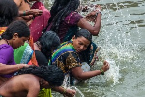 Primo piano di alcune donne Hindu che si sottopongono gioiosamente al rito del bagno sacro per purificarsi, abbandonarsi e depurarsi dalle energie negative accumulate. L'acqua, la terra ed il fuoco sono da sempre i tre elementi naturali sui quali si basa la loro vita quotidiana ed il loro credo religioso. In occasione di queste celebrazioni, divengono le tre tappe fondamentali per giungere alla purificazione del corpo e dell'anima. Piscina alimentata dal Saundatti Lake, villaggio di Saundatti, Regione del Karnataka, India 2015.