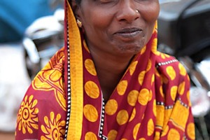 Alopa, una giovane donna Hindu si copre il capo dal sole accecante con un canovaccio ripiegato a mò di copricapo: divertita, si mostra cordialmente all'obiettivo della mia macchina fotografica. Anche lei è giunta sino al villaggio di Saundatti per essere presente durante le celebrazioni in onore della Dea Yallamma. Regione del Karnataka, India 2015.