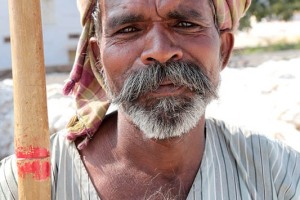 Ashwatthama, operaio della Sha Shivalal Jawaharlal Jain di 43 anni, accetta di posare per il mio obiettivo fotografico con la sua inseparabile pertica di bambù (utilizzata per issare sui camion le enormi balle di cotone): il suo sguardo è tra il curioso ed il divertito. Dintorni del villaggio di Saundatti, Regione del Karnataka, India 2015.
