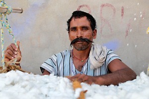 Abhisar, operaio indiano di 32 anni, si appresta a chiudere la grande balla di cotone contenuta nella rete di corde intrecciate a mano che verrà poi immagazzinata per il successivo carico sul camion che la trasporterà, dintorni del villaggio di Saundatti, Regione del Karnataka, India 2015.