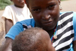 Mamma appartenente all'etnia Djerma Songhai, tiene in braccio la sua bambina lungo le sponde del fiume Niger, 2019