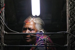 Anziana donna Gurung affacciata alla sua finestra osserva il via vai nella piazza sottostante, Villaggio di Chapagaon, Nepal 2018.