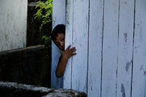 Un bambino di etnia Gurung, curioso, fa capolino dalla porta della sua abitazione, villaggio di Gorkha, Nepal 2018.