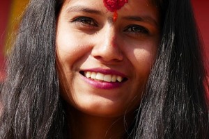 Una giovane ragazza nepalese appartenente all'etnia Gurung è appena uscita dal sacro Tempio di Pashupatinath dopo le preghiere di rito: presenta sulla fronte un vistoso "Tilaka" di colore rosso, segno  praticato sulla fronte dei devoti dal sacerdote a testimonianza della visita effettuata nel Tempio. Inoltre ha, sempre sulla fronte, un "kumkum" una mistura di polvere di curcuma e pasta di sandalo dal colre giallo arancione. Il colore giallo è il colore della conoscenza e dell'apprendimento, simboleggia felicità, pace, meditazione, competenza e sviluppo mentale. E' il colore della primavera ed attiva positivamente la mente. Nepal 2018.