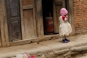 Dinanzi alla casa di questa bambina Gurung vi è una bella statua in pietra riproducente una mucca sacra: è considerata l'incarnazione del Signore Laxmi, il Dio della ricchezza. Secondo la tradizione che si perde nella notte dei tempi, qualsiasi famiglia che abbia perso un parente durante l'anno appena trascorso, deve partecipare ad una processione con una vacca al guinzaglio, oppure se non riuscisse a portare una mucca può sostituirla con un giovane che sia disponibile a travestirsi: si crede che questo animale possa aiutare i parenti defunti ad arrivare in paradiso. Gli Hindu non considerano la mucca una vera e propria Divinità e non la adorano. In essa vedono un simbolo sacro della vita che va protetto e riverito. Villaggio di Panuati, Nepal 2018.