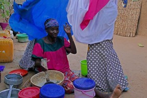 Mentre la mamma prepara il pranzo, la figlia le pone il velo sulle spalle, etnia Haoussa, villaggio Mouja, Niger 2019