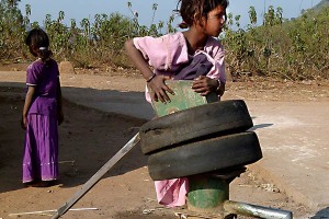 Ad un pozzo che fornisce l'acqua al villaggio di Kakkabe, Charulekha, una bambina Kodavas di otto anni, gioca arrampicandosi sulla cima della fontana. Distretto di Kodagu, Regione del Karnataka, India 2015.