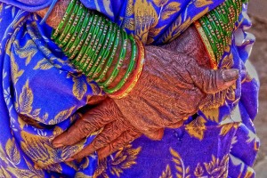 Primo piano delle mani incrociate di questa anziana donna Kodavas: sono evidenti i segni del tempo, della fatica e delle privazioni. Raccontano di una vita di stenti ma anche dignitosa, lo dimostrano i bracciali che indossa con eleganza ed il sari dalla ricercata fantasia. Villaggio di Kakkabe, Distretto di Kodagu, Regione del Karnataka, India 2015.