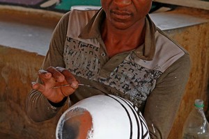 Uomo di etnia Ndbele pratica gli insegnamenti delle proprie donne decorando i vasi di ceramica con antichissime tecniche tramandate di generazione in generazione, Regione Mpulamanga, Villaggio Botshabelo, Sud Africa 2012