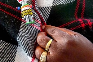 Una spilla riproducente una bambolina realizzata a mano con le perline colorate da una donna Ndebele, ferma i due lembi della coperta che indossa, villaggio di Kglodwana, Regione del Mpulamanga, Sud africa 2012