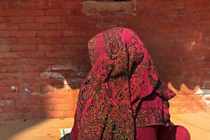 Una donna Newari prega accovacciata a terra davanti all'ingresso del Tempio d'Oro, un Tempio buddhista risalente al 1409; prende il suo nome dalle lamine dorate che ricoprono gran parte della facciata, Patan, Nepal 2018