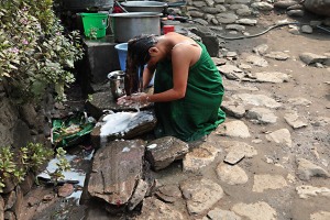 Lungo la strada che porta a Bandipur, prima di arrivare a questa incantevole città del Nepal culla della cultura Newari, all'interno di un cortile che circonda una piccola abitazione rurale, una ragazza nepalese si lava i capelli inginocchiata sul selciato. Nepal 2018