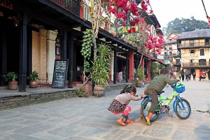 Nella strada principale della città di Bandipur due bambini nepalesi dell'etnia Newari giocano con una bicicletta, Nepal 2018
