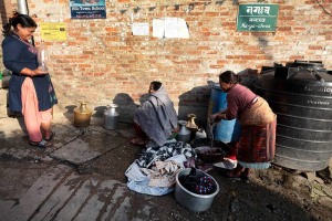 Donne Newari lavano le loro vesti e fanno rifornimento d'acqua riempiendo bottiglie ed anfore che poi trasporteranno a piedi sino alla loro abitazione, villaggio di Kirtipur, Nepal 2018.