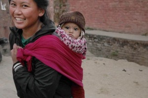 Una giovane mamma Newari porta sulla schiena la sua bambina tra le strade del villaggio di Kirtipur, Nepal 2018.