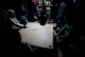 Il "Carrom" è un antichissimo gioco orientale di abilità simile, sotto certi versi, al biliardo (infatti viene denominato anche come biliardo da dita): occorre imbucare le proprie pedine attraverso lo "striker", una pedina neutra che deve essere colpita con un solo dito. Serve un tavolo quadrato con i bordi rialzati, 21 pedine (9 nere, 9 bianche, 2 striker ed una rossa), mentre sulla superficie vengono disegnate delle figure geometriche utili per lo svolgimento della competizione. Qui un gruppo di giovani nepalesi di etnia Newari sono concentrati nel  gioco, Villaggio di Kirtipur, Nepal 2018.