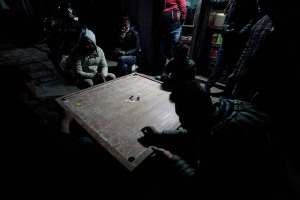 Un momento appassionante del gioco "Carrom" : il lancio dello "striker", la pedina neutra che viene colpita con un solo dito per imbucare le proprie pedine. E' un antichissimo gioco orientale di abilità simile, sotto certi versi, al biliardo (infatti viene denominato anche come biliardo da dita). Serve un tavolo quadrato con i bordi rialzati; 21 pedine (9 nere; 9 bianche; 2 striker ed una rossa); mentre sulla superficie vengono disegnate delle figure geometriche utili per lo svolgimento della competizione. Villaggio di Kirtipur, Nepal 2018.