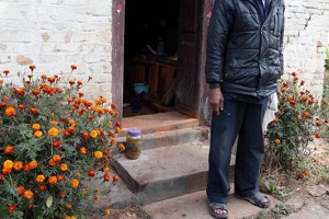 Uomo Newari davanti all'ingresso della sua abitazione: i fiori, le decorazioni dipinte a mano e gli stendardi buonaugurali sull''architrave e sul telaio della porta di accesso sono molto diffuse tra tutti gli abitanti del Nepal, anche di etnie diverse. Nepal 2018.