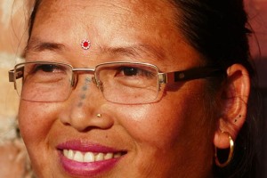 La mamma di Hira Thapa, oltre al classico "Bindi" (in questo caso acquistato a scopo decorativo), presenta sul volto una serie di puntini tatuati (sul naso ed ai due lati del mento), il cui significato è per me sconosciuto (pur avendolo chiesto alla diretta interessata, non sono riuscito a comprenderne la motivazione). Villaggio di Kirtipur, Nepal 2018.