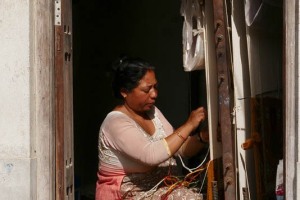 Una donna Newari fila la lana con il telaio accanto all'entrata della sua abitazione, villaggio di Khokanà, Nepal 2018.