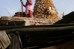 Una sentinella sul tetto? No, è semplicemente una donna Newari che ha costruito una "torre" con le pannocchie di granoturco perchè si asciughino bene al sole, villaggio di Khokanà, Nepal 2018.