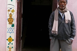 Questo uomo Newari di nome Bijaya Ratna ha dipinto la cornice esterna della porta d'ingresso della sua abitazione con simboli religiosi e di buon auspicio (dal simbolo dell'Om, al Dio Ganesh e via dicendo), villaggio di Khokanà, Nepal 2018.