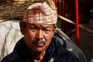 Un uomo Sherpa con il tipico copricapo: questo gruppo etnico, composto anticamente da pastori nomadi, giunse dal Tibet circa 500 anni addietro, introducendo il buddhismo tibetano e costruendo i magnifici "gompa" (monasteri) che sfidano la gravità sui fianchi delle montagne. Molti di loro attualmente svolgono il lavoro di guide di alta montagna o sono proprietari di agenzie di viaggio. Una minoranza continua, invece, a svolgere lavori pesanti e disagievoli. Pokhara, Nepal 2018.