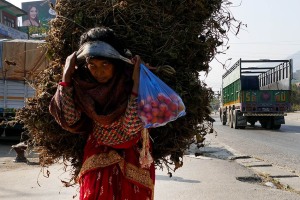 Sotto il peso di questa enorme balla di fieno destinata agli animali, questa donna nepalese appartenente all'etnia Sherpa, percorre a piedi la strada che da Bungamati porta al villaggio di Khokana, Nepal 2018.
