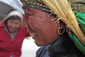 Primo piano di una donna Tamang con la caratteristica fascia posta sulla testa al fine di equilibrare e sorreggere il peso del carico, città di Bandipur, Nepal 2018