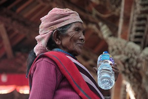 Anziana donna appartenente all'etnia Tamang, passeggia con la sua bottiglia d'acqua sotto la tettoia di Keshav Narayan Chowk, nella città di Patan (in sanscrito Laliptur, "Città della Bellezza"), Nepal 2018.