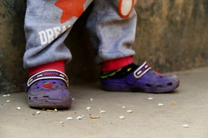 Sul pavimento in cemento restano i chicchi di riso che questo bambino Tamang non è riuscito a mangiare dalla sua ciotola (il nome Tamang in tibetano significa "mercanti di cavalli": anticamente gli antenati di questo bimbo sono entrati in contatto con le popolazioni locali per fini commerciali; sino a sedentarizzarsi nei territori dell'attuale Nepal; attualmente svolgono frequentemente l'attività di portatori al pari degli Sherpa basandosi sulla loro profonda conoscenza delle montagne facenti parte del Massiccio montuoso dell'Himalaya; il Buddhismo è molto diffuso, anche se spesso contaminato con elementi dell'antica religione "Bon"; il Lama, cioè il sacerdote, ha un ruolo fondamentale all'interno della comunità celebrando matrimoni e funerali; numerosi clan Tamang vietano il matrimonio interetnico mentre altri lo consentono limitatamente ai membri delle etnie Gurung, Magar, Newari e Chhetri; è comunque proibito il matrimonio all'interno dello stesso clan). Nepal 2018.