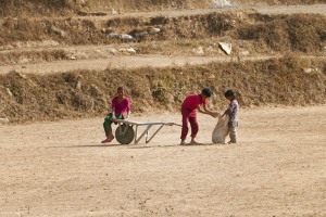Anche i bambini Tamang lavorano all'interno del cantiere: qui il fratello più grande aiuta la sorellina a caricare sulla carriola un pesante sacco contenente sassi, dintorni del villaggio di Chapagaon, Nepal 2018.