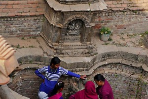 In un fontanile anticamente usato come cisterna per i riti delle abluzioni sacre, alcune donne di etnia Thakali raccolgono l'acqua in bidoni di plastica o vasi di metallo che poi porteranno a piedi nelle rispettive abitazioni del villaggio di Tukche, Nepal 2018.
