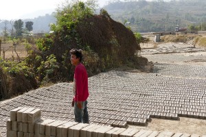 Una fabbrica di mattoni: un ragazzo di etnia Thakali sistema i mattoni al sole per farli asciugare, villaggio di Chabahil, Nepal 2018.