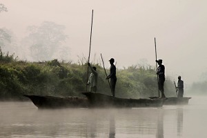 Nel Chitwan National Park ("Chitwan" significa Cuore della Giungla), che si estende per oltre 932 chilometri di foreste, paludi e praterie, il fiume Rapti scorre lento tra la bruma del primo mattino, mentre gli uomini di etnia Tharu si muovono lentamente sulle loro piroghe che spingono con lunghi bastoni di legno sul fondo del fiume (queste imbarcazioni sono ricavate direttamente dai tronchi scavati a mano), Chitwan National Park, Nepal 2018