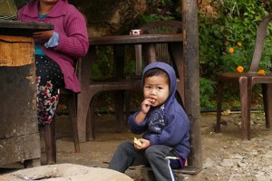 Un bambino Tharu di nome Kumar con la sua mamma nel cortile esterno della loro abitazione: si narra che un vecchio saggio capoclan Tharu potesse comunicare con gli elefanti mediante la loro lingua madre e questo lo considerava un dono divino. Villaggio di Harnari, Nepal 2018.