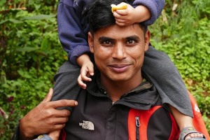 Un giovane papà Tharu con il suo bambino sulle spalle: lavora come guida naturalistica nel Chitwan National Park, Nepal 2018.