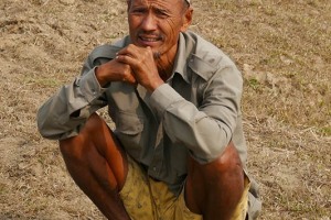 Un contadino Tharu si riposa, dopo aver tagliato con la roncola la legna, mentre il suo fedele cane mi osserva attento, Chitwan National Park, Nepal 2018.