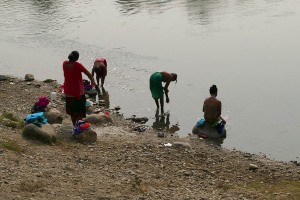 Alcune donne Tharu si bagnano al fiume Rapti e fanno il bucato, Chitwan National Park, Nepal 2018.