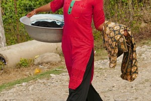 Una giovane ragazza Tharu rientra nel villaggio con il bucato appena lavato, villaggio di Harnari, Chitwan National Park, Nepal 2018.