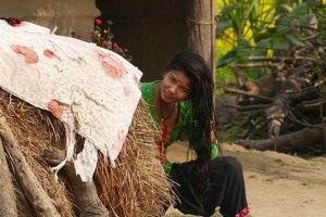 Una giovane ragazza di etnia Tharu si asciuga i capelli al sole fuori della sua capanna nel villaggio di Harnari, Chitwan National Park, Nepal 2018.