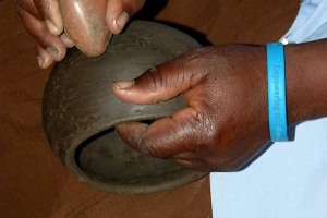 Particolare di una fase di lavorazione di un vaso di argilla: viene sfregata, dalle abili dita della donna Venda, una particolare pietra che effettua la lucidatura della superficie esterna, Provincia del Limpopo, Sud Africa 2012