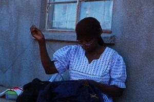 Nel Villaggio Xhosa di Elundini una donna cuce le decorazioni di perline ed i ricami su un vestito, Sud Africa 2012
