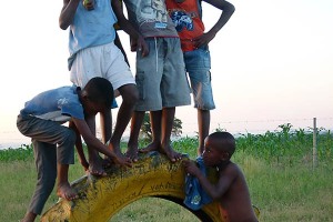 Bambini Xhosa giocano arrampicandosi su una ruota abbandonata di un camion, dintorni del villaggio di Lesedi, Sud africa 2012